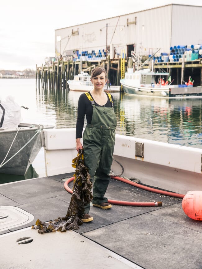 A woman in work clothes standing on a dock.