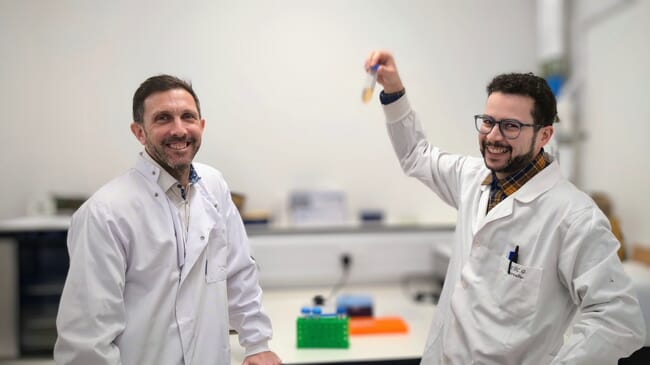 Two men in labcoats, one holding a test tube.
