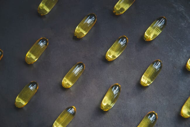 Alligned omega-3 capsules on a black background.