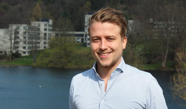 A man standing in front of a large pond.